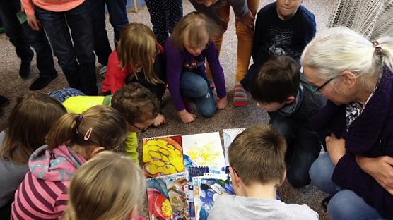 Johanna Kerwitz (rechts im Bild) zeigt den Kindern die Originalzeichnungen zum Kinderbuch Maries Kuschelkissenkn&ouml;pfe (Foto: S. Dre&szlig;ler)