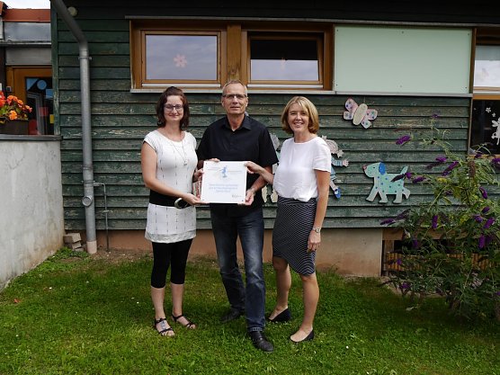 Bei der &Uuml;bergabe der Plakette erfreuen (sich im Bild v.l.n.r.), die zus&auml;tzliche Fachkraft Mar&egrave;n Laub, der B&uuml;rgermeister der Gemeinde Werther Hans J&uuml;rgen Weidt und die Kita Leiterin Beanke Juch. (Foto: Beanke Juch)