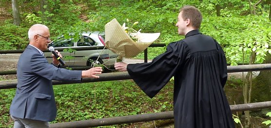 Pr&auml;ses Dr. Uwe Krieger &uuml;bergibt den Blumengru&szlig; des Kirchenkreises coronagerecht und sehr schwungvoll. (Foto: R. Englert)