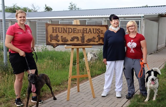 Holzschild f&uuml;r neues Hundehaus, v.l.n.r.: Sandra M&uuml;hle, Gesch&auml;ftsstellenleiterin des Tierheims, K&uuml;nstlerin Tura Jursa, Jennifer Schenk, Leiterin des Tierheims. (Foto: Stadtverwaltung Nordhausen)