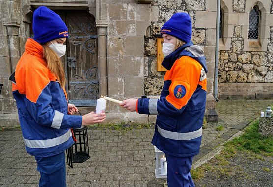 Joceline (links) aus Harzungen empf&auml;ngt von Emily vor der Kirche in Niedersachswerfen das Friedenslicht. (Foto: Susanne Schedwill)