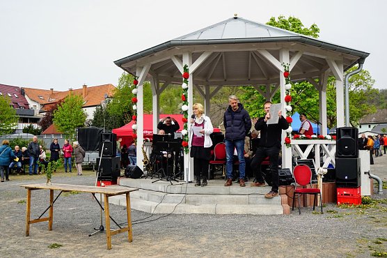 Ortschaftsb&uuml;rgermeisterin Petra Gerlach und Ortschaftsrat  Matthias M&uuml;gge pr&auml;sentieren das Sponsorenschild. Ein Gro&szlig;teil der 65 Spender hatte sich zum Foto unter dem Maibaum eingefunden. (Foto: Susanne Schedwill )