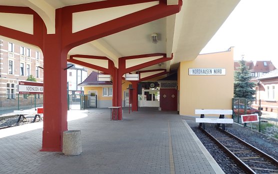 Blick vom Bahnsteig zum Empfangsgeb&auml;ude, unter dem Bahnhofsschild gab eine Fensterreihe den Blick der Aufsicht auf den Bahnsteig frei, vor der hintersten S&auml;ule sperrte die h&ouml;lzerne bahnsteigsperre den unbefugten Weg zu den Gleisen ab, hinter der kleinen braunen Doppelt&uuml;r befand sich die Gep&auml;ckabfertigung und links befanden sich die Toilettenanlagen. Ganz links hinter dem neuen Zaun (fr&uuml;her eine Mauer), f&auml;hrt auf der Oscar-Cohn-Stra&szlig;e die Linie 10 der Nordh&auml;user Stra&szlig;enbahn nach Ilfeld Neanderklinik vom Bahnhofsplatz vorbei.  (Foto: W.Schwarzbach)