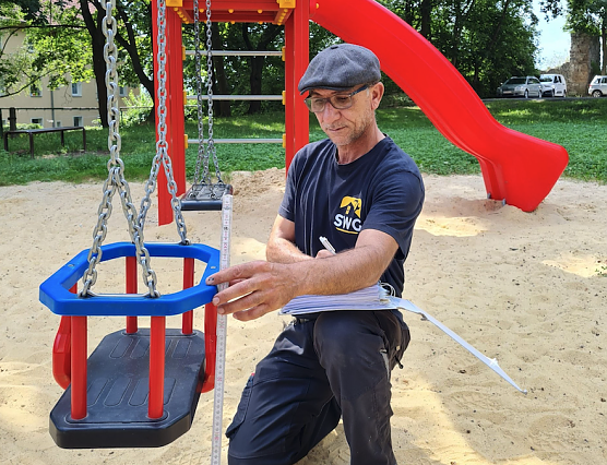 Tuncay Inanc misst auf dem Spielplatz in der Predigerstra&szlig;e die Schaukelh&ouml;he genau nach.  (Foto: SWG Nordhausen/S.Schedwill)