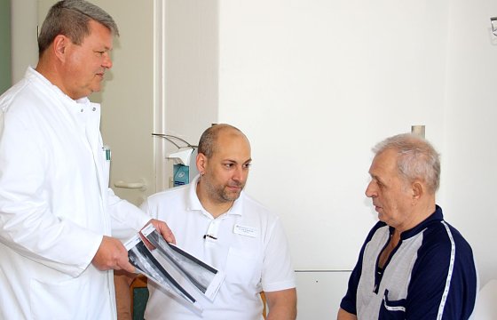 Bild: Michael Huttasch (li.) und Dr. Andreas Ubl (Mitte) zeigen Josef Heinz die R&ouml;ntgenbilder mit der Verst&auml;rkung seiner Wirbels&auml;ule nach der OP