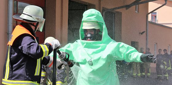 Bild: Ein Feuerwehrmann im Schutzanzug wird zu &Uuml;bungszwecken dekontaminiert.