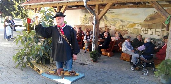 Bild: Brockenbauer Uwe Thielecke erl&auml;utert der Reisegruppe der Landsenioren aus dem S&uuml;dharz seinen Bauernhof. Vor ihm auf dem Holzbrett: Wurstspezialit&auml;ten des Hauses.