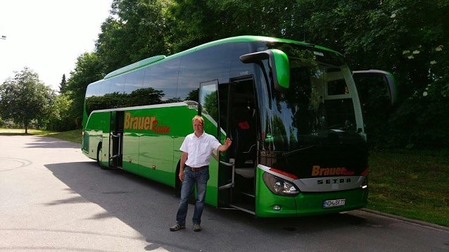 Bild: Roland Merx vor seinem hochmodernen Reisebus.