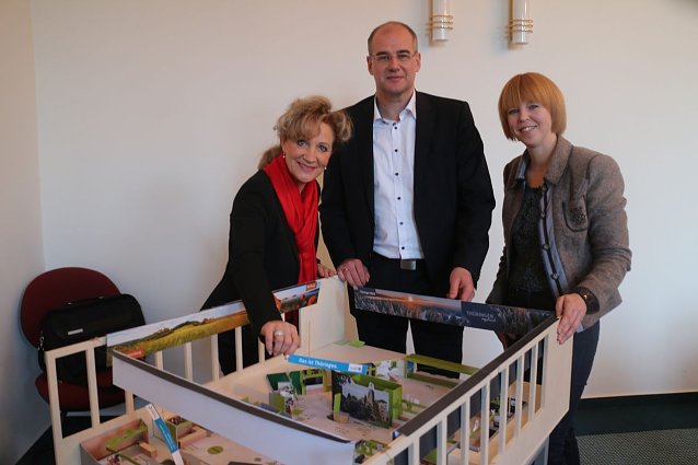 Bild: v.l.: Ministerin Birgit Keller, Landrat Matthias Jendricke und Jessica Pieper vor dem Modell des Th&uuml;ringer Messeauftritts