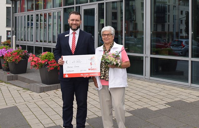 Bild: Kundenberater Daniel Czerwinski &uuml;berreicht der gl&uuml;cklichen Gewinnerin den symbolischen Scheck.