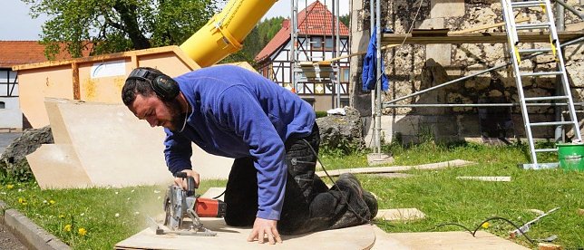 Bild: Zimmermann Alexander Vins schneidet Hartfaserplatten, die als Fensterschutz dienen.