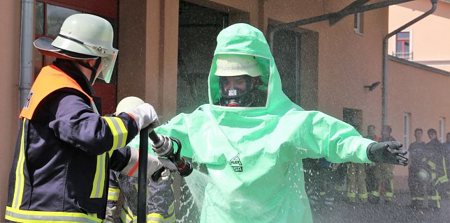 Bild: Ein Feuerwehrmann im Schutzanzug wird zu &Uuml;bungszwecken dekontaminiert.