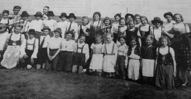 Bild: Dieses Foto entstand am 1. Mai des Jahres 1950. Es zeigt den damaligen Schulchor. Ganz links Erika Nebelung mit Gitarre, dahinter Lehrer Gerhard Stolz. Im Hintergrund rechts daneben Schulleiter Otto Lerp.