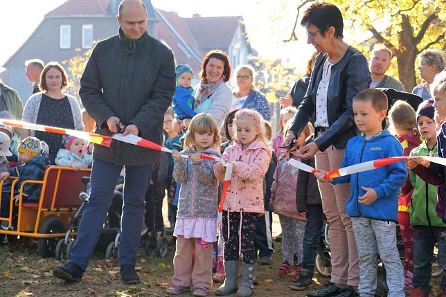 Bild: Henry Pasenow und Helga Tamaschke erhalten von den Kindergartenkindern beim Banddurchschnitt Hilfe. 