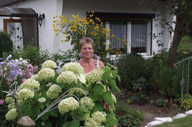 Kerstin Pabst versteckt hinter pr&auml;chtigen Blumen vor dem Bungalow. (Foto: Kurt Frank)