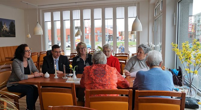 Sandra Hoche, Christian D&ouml;ring und Inge Klaan (v.l.n.r.) im Gespr&auml;ch mit SWG-Mietern im Caf&eacute; Mittendrin in Nordhausen-Salza. Die vier Damen  auf dem Bild rechts geh&ouml;ren zu den Stammg&auml;sten, nutzen das Fr&uuml;hst&uuml;cks- und Mittagsangebot regelm&auml;&szlig;ig. (Foto: Susanne Schedwill/SWG Nordhausen)