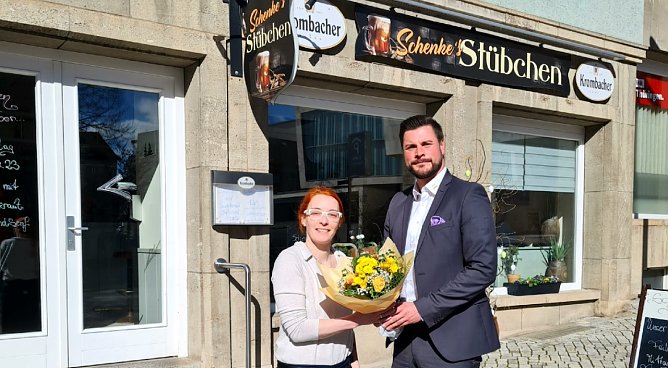 Christin Klein ist seit M&auml;rz die Chefin hinter dem Tresen von Schenkes St&uuml;bchen am Nordh&auml;user Markt. Pascal Wetzler von der SWG &uuml;berbrachte Blumengr&uuml;&szlig;e zum Start. (Foto: SWG Nordhausen/Schedwill)
